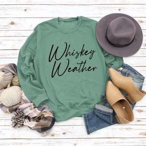 Flat lay of sage green sweatshirt with Whiskey Weather text and autumn accessories
