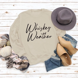 Flat lay of Whiskey Weather sweatshirt with autumn accessories on white wood floor