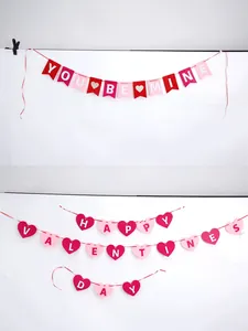 Red and pink Valentine's felt banners with heart and fishtail shapes on white wall