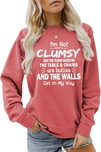 Close-up of white letter print on a brick red crewneck sweatshirt with ribbed cuffs