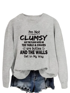 Detail of grey crewneck sweatshirt featuring humor text and ribbed cuffs texture