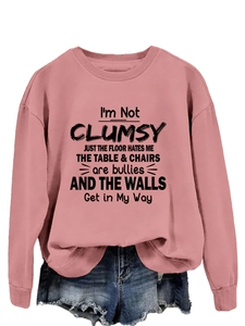 Detail of pink crewneck sweatshirt with black humorous quote and ripped denim shorts