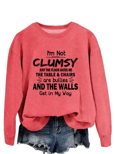 Detail of red crewneck sweatshirt featuring black humorous text with denim shorts