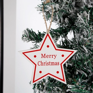 Stella in legno decorativa Merry Christmas appesa a un ramo di albero di Natale innevato