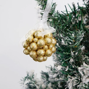 Golden glitter Christmas tree ball ornaments with white ribbon bow hanging on snowy branch