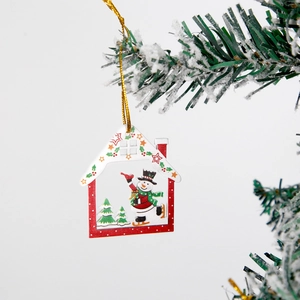 Christmas wooden house ornament with skating snowman hanging on a snowy pine branch