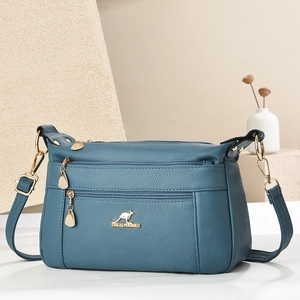 Detail of teal blue crossbody bag with lychee texture and golden kangaroo logo hardware