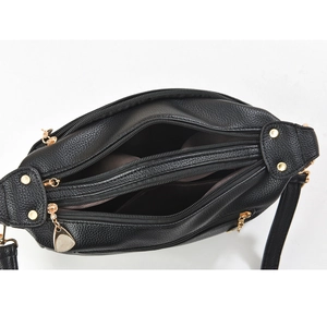 Detail view of black pebble leather crossbody bag with four golden zipper compartments