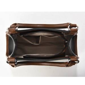 Vue intérieure du sac selle marron montrant la poche zippée et la doublure lisse