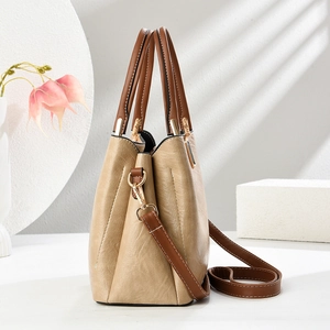 Detail of beige textured leather tote bag with brown handles and gold-tone hardware