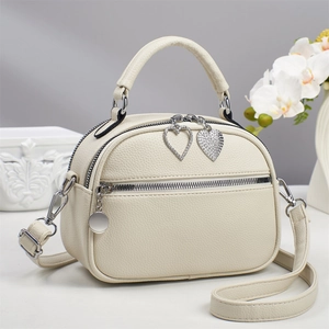 Close-up of cream white lychee leather bag with heart-shaped diamond zipper charms
