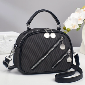 Elegant black textured handbag with diagonal zippers and adjustable shoulder strap