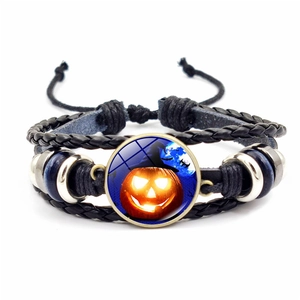 Macro detail of Halloween woven leather bracelet with glowing pumpkin glass cabochon