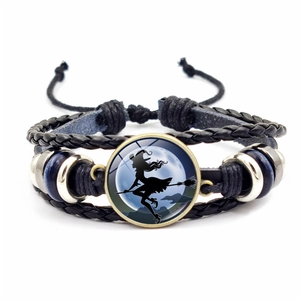 Detail of Halloween woven leather bracelet featuring a witch silhouette glass pendant
