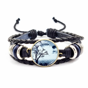 Macro shot of Halloween glass gem bracelet with moon and tree pattern on leather