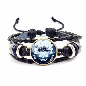 Macro view of woven Halloween bracelet featuring a pumpkin skull glass gem and blue beads