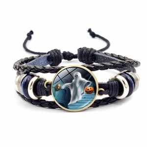 Detail of woven leather Halloween bracelet with ghost and pumpkin glass dome