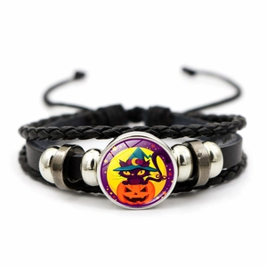 Detail of woven leather Halloween bracelet featuring a witch cat and glowing pumpkin charm
