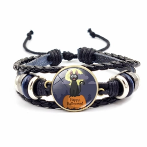 Dettaglio del bracciale in pelle intrecciata con ciondolo a tema zucca e gatto di Halloween