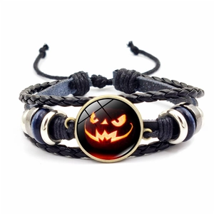 Dettaglio del cabochon con zucca di Halloween su bracciale in pelle intrecciata multistrato