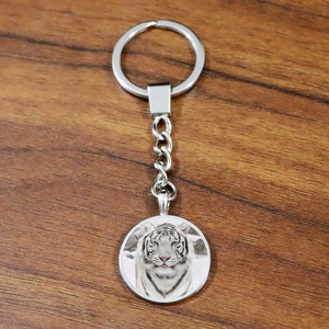 Siberian white tiger glass gem keychain with silver metal alloy ring on wooden surface