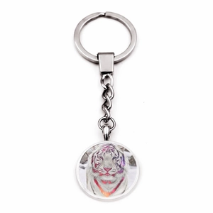 Detail shot of a metal keychain with a clear glass dome showing a white tiger face