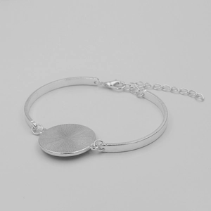 Detail of silver half-moon bracelet with sunburst textured round pendant and lobster clasp