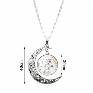Collier lune argenté avec cabochon en verre et verset sur un fond blanc neutre