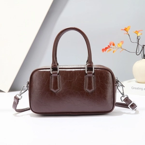 Close-up of vintage brown leather Boston bag with polished silver hardware and strap