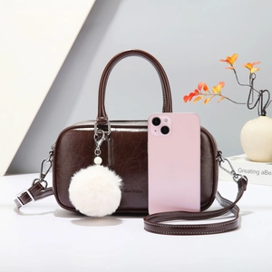 Detail view of dark brown faux leather Boston bag with a white pompom and size reference