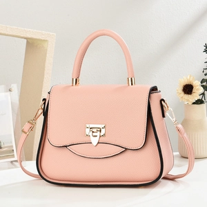 Close-up of pink litchi grain leather handbag with gold metal lock and round handle