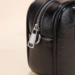 Close-up of black cracked leather bowling bag with white stitching and silver hardware