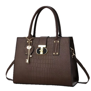 Dark brown crocodile textured handbag with golden T-lock and elegant key charm pendant