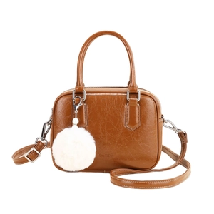 Brown bowling shoulder bag in oily leather texture with white faux fur pompom charm