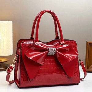 Detail of red crocodile texture handbag with rhinestone bow and gold hardware