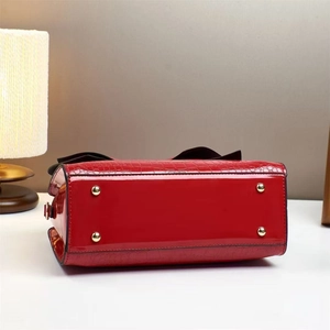 Detail view of red faux crocodile leather handbag with four silver protective bottom studs