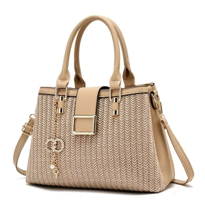 Detail of beige crossbody bag showing V-weave texture and golden ring pendant accessory