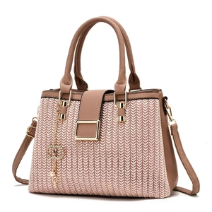 Detail of woven texture pink handbag with brown leather accents and gold chain link