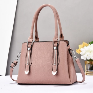 Detail of pink lychee leather handbag with silver vertical metal trim and heart studs