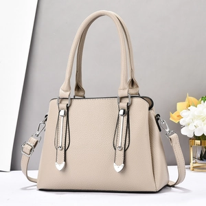 Elegant beige pebbled leather handbag with metal accents and adjustable shoulder strap
