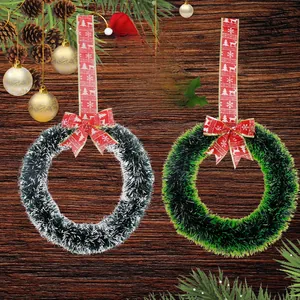 Close-up of Christmas wreaths with red reindeer ribbons on dark wood background