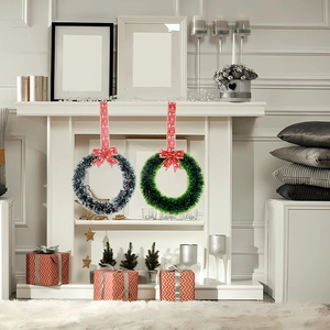 Close-up of Christmas wreath with red bow hanging on a white fireplace for home decor