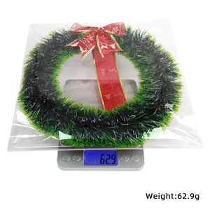 Christmas wreath with red bow and reindeer pattern being weighed at 62.9g on a scale