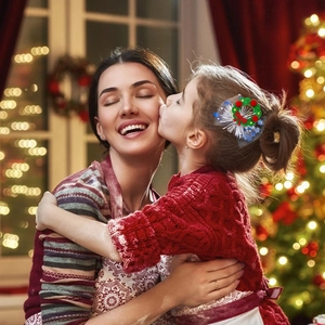 Girl wearing a festive green Christmas wreath hair clip with red bow and white snowflakes