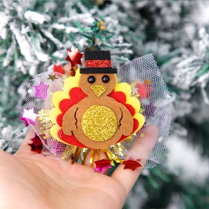 Detail of felt turkey hair clip with gold glitter accents and festive mesh stars
