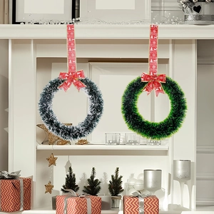 Christmas wreath with festive red bow and white snow-tipped green branches on fireplace