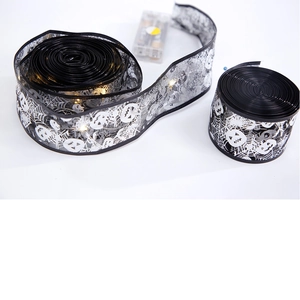 Detail of Halloween LED black mesh ribbon featuring silver spider web and pumpkin patterns