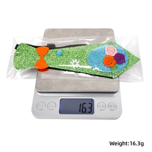 Detail shot of green glitter Easter tie with cute fabric flowers and weight on scale