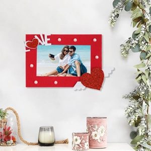 Close-up of red felt photo frame with LOVE lettering, white pearls and glitter heart wings