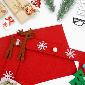 Detail of red Christmas felt envelope with reindeer decal on festive desktop setup